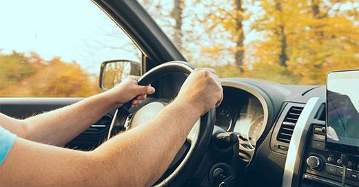 Une personne avec les mains sur le volant d'une voiture