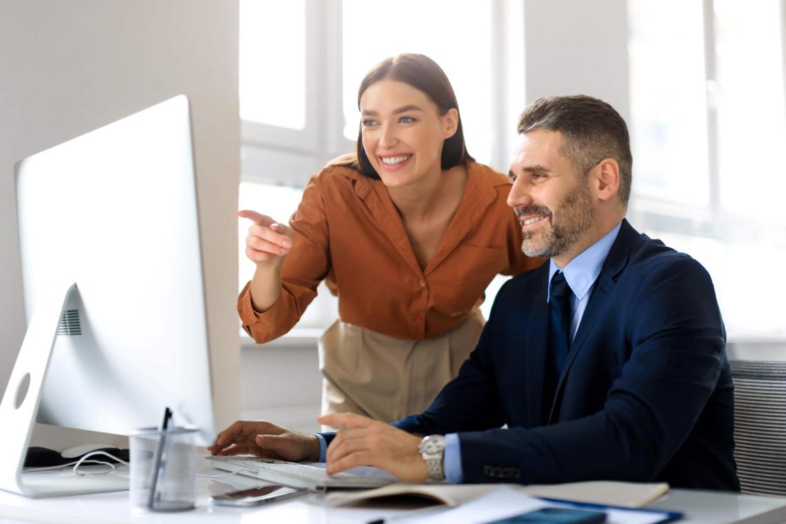 Woman standing next to man, pointing at screen