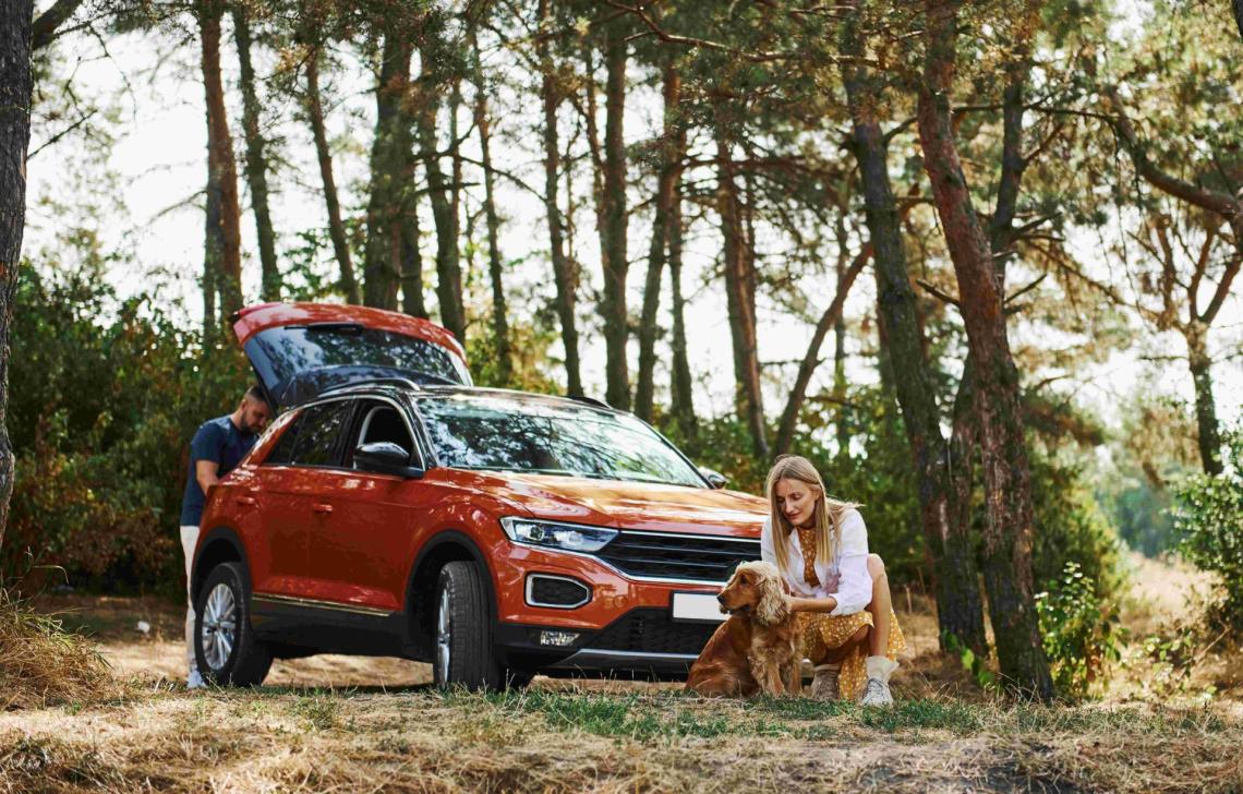 Woman, man and dog in front of car